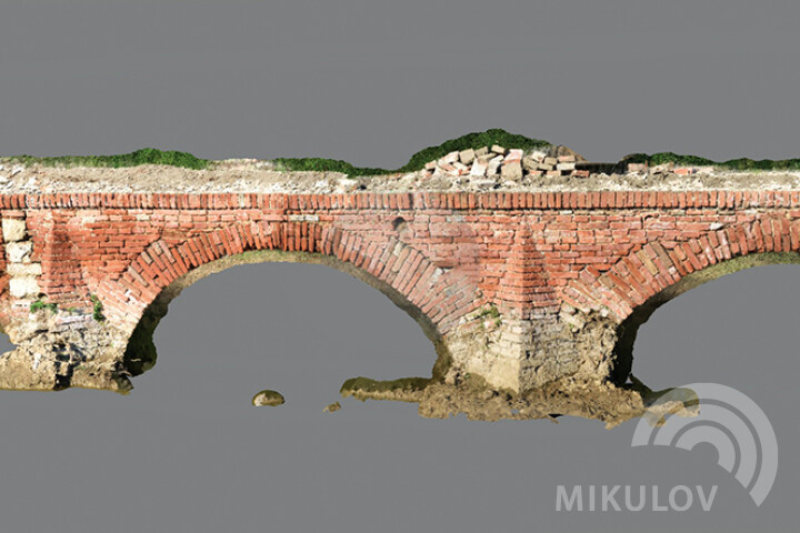 Na obrázku je zachycen výřez z celkového 3D modelu mostu za pomoci laserového skenování mostu provedeného v rámci archeologického průzkumu v roce 2019. Skenování bylo prováděno z důvodu zmapování rozsahu dochování původních konstrukcí mostu. Na prvním oblouku zleva je viditelná dodatečná úprava mostu dozděním klenby po původním dřevěném padacím mostu. Zdroj: Ing. Miloš Tejkal